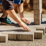 man laying down concrete bricks